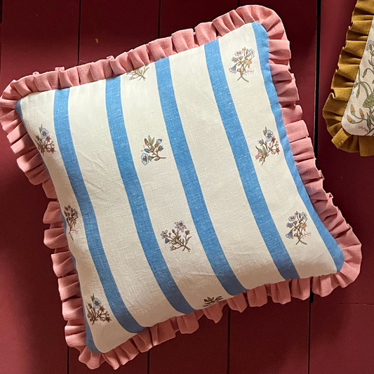 cushion with coral frill and blue stripe floral print on a red background